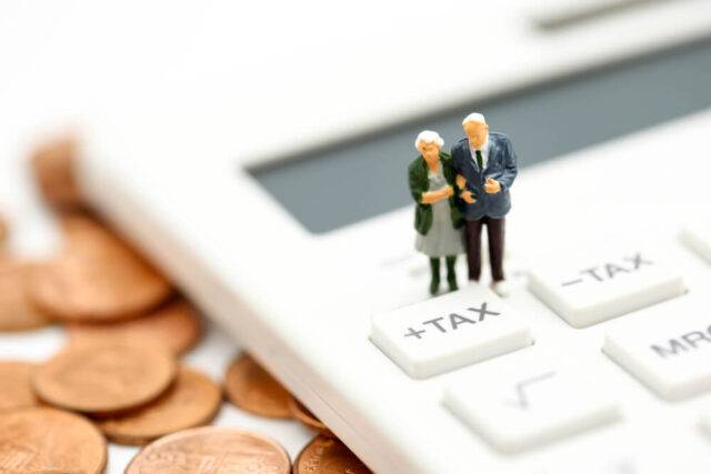 image of a couple of old people stood on a calculator surrounded by money, they are stood next to the how to reduce tax button and the image is a metaphor for how to reduce inheritance tax on bonds